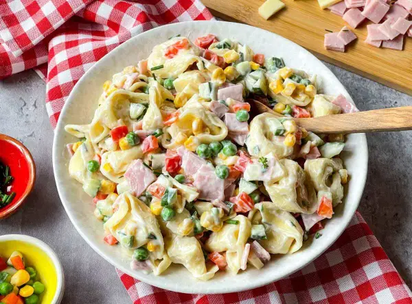 Cremiger Tortellini Salat mit Erbsen, Mais, Paprika und Schinken. Ein perfekter Sommergenuss!