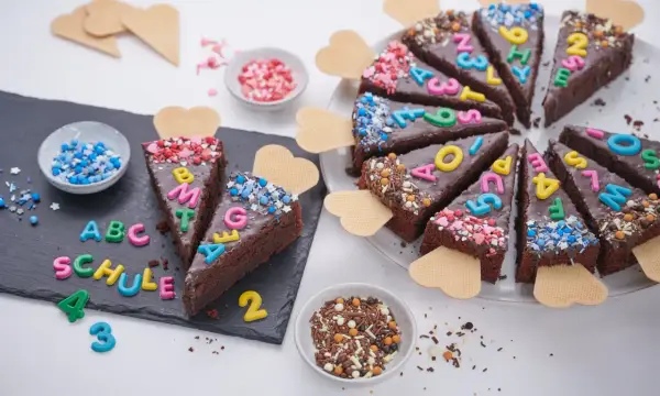 Schokoladenkuchenstücke mit bunten Buchstaben und Zahlen, die "ABC SCHULE" ergeben. Ein perfekter Kuchen zur Einschulung!